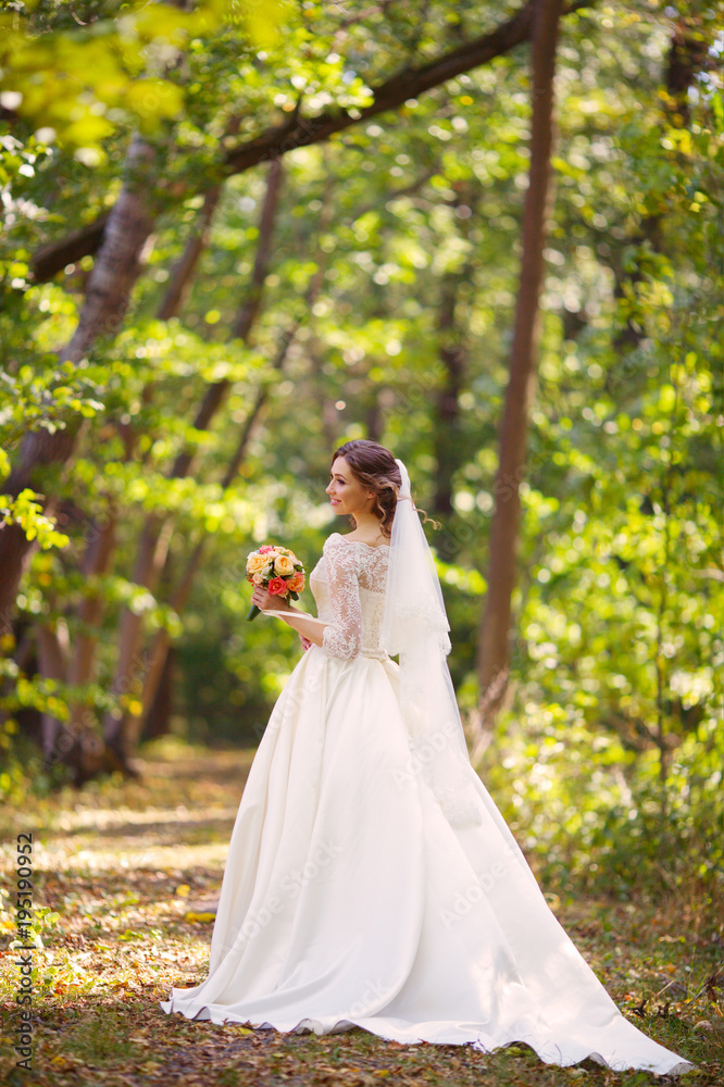 Bride at wedding Day walking Outdoors on nature. Happy Newlywed woman embracing in green park Bride at wedding Day walking Outdoors on nature. Happy Newlywed woman embracing in green park