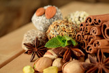 Sweets with different sprinkles, cinnamon, anise stars, mint and pistachio nuts on wooden boards