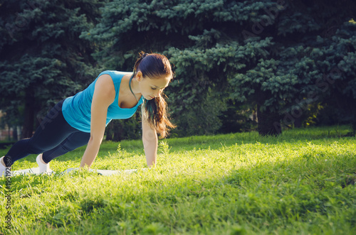 Beautiful girl doing sports exercises outdoors.