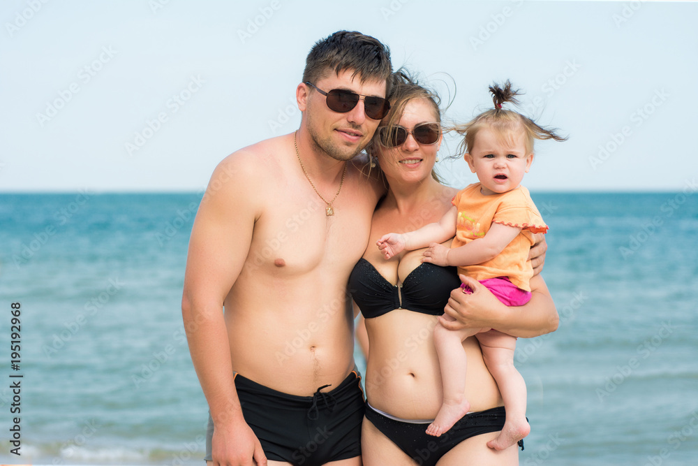 Young parents are holding a small daughter on the back of the sea and the sky Young parents are holding a small daughter on the back of the sea and the sky