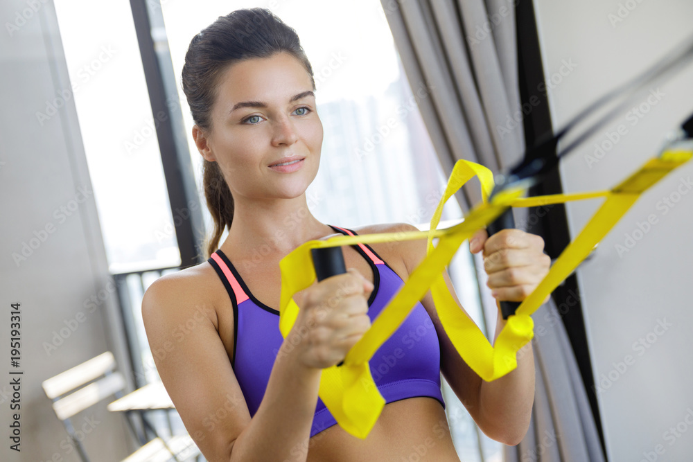 Woman during her  workout at home with suspension straps