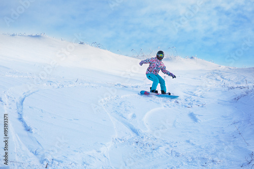 One snowboarder ride from a high snowy mountain under a blue sky.