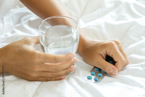 Female hands with a glass of water and pills