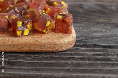 Turkish joys with different nuts are a glass of tea and a spoon. Eastern sweets. Traditional Turkish delight (Rahat lokum) on a wooden background. Side view. photo