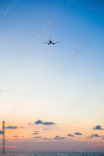 Airplane flying above sea at sunset