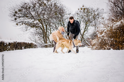 A lovely couple plays with her dog in a snowy park photo