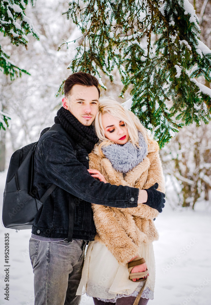 A lovely couple standing in a hug near a tree with their dog A lovely couple standing in a hug near a tree with their dog