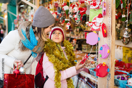 Happy mother with little daughter buying decorations for Xmas