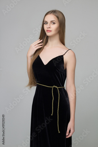 Young beautiful long-haired girl stands in black dress