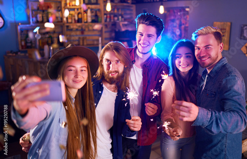 Selfie Time.Young Group of Friends Partying In A Nightclub And Toasting Drinks. Happy Young People With Sparklers At Pub. The People Have A Great Mood And They Smile A Lot.