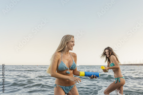 Young woman shooting her friend with a water gun