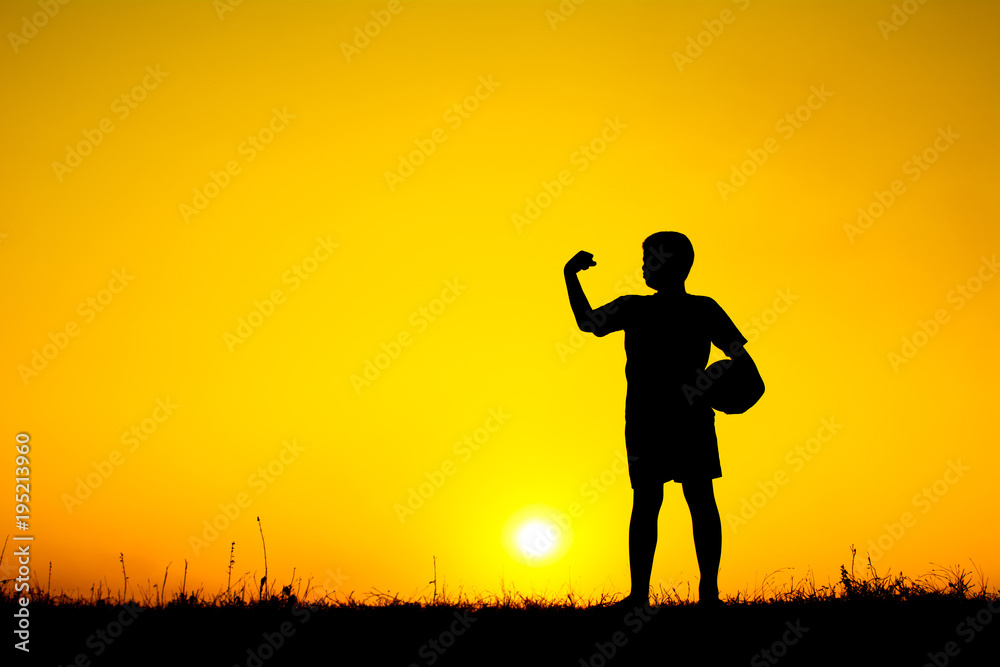 Silhouette of boy playing football during sky sunset background Silhouette of boy playing football during sky sunset background