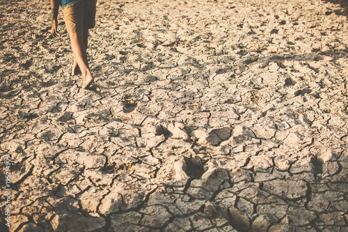 Feet of boy walking on cracked dry ground .concept hope and drought