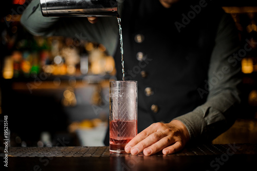 Bartender is making cocktail at the bar counter