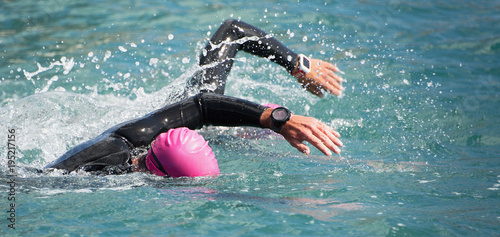 Obraz na plátně Triathlon long distance swimming, people in wetsuit swimming at triathlon