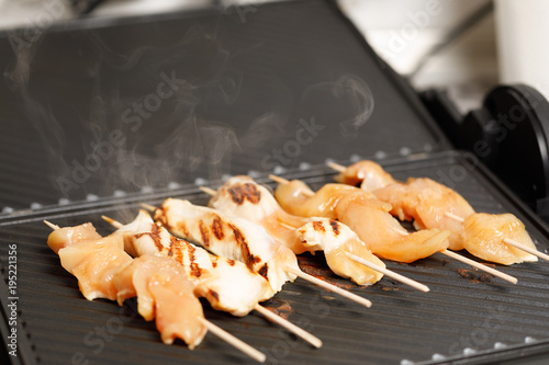 closeup of chicken skewers on electric grill