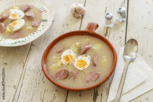 Clay pot and plate of traditional polish soup called Zurek