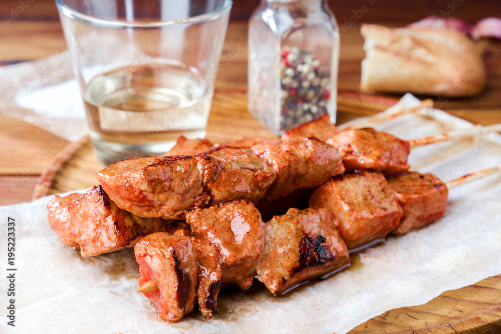 skewer of spiced pork roasted on barbecue on wood