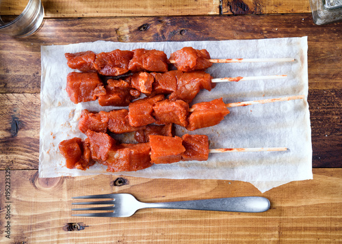 skewer of raw marinated meat on wood photo