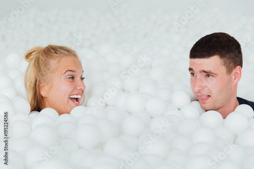 couple of loving friends have fun surrounded by white plastic balls in a dry swimming pool. photo