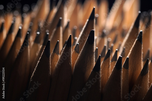 Bunch of identical graphite pencils on black background