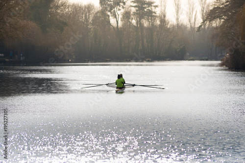 Photographie two people rowing in a boat with blades in the early morning shimmering light