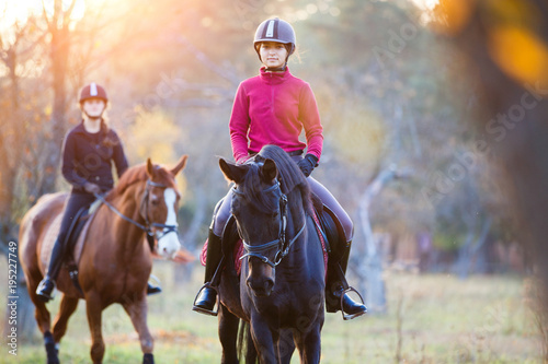 Group of rider girls riding their horses in park. Equestrian recreation activities background with copy space
