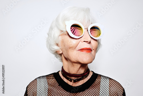 Smiling senior woman in stylish sunglasses and shirt