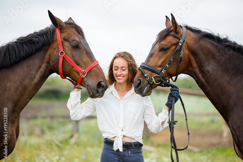 Young rider girl having fun with two her horses. Equestrian sport concept background © skumer