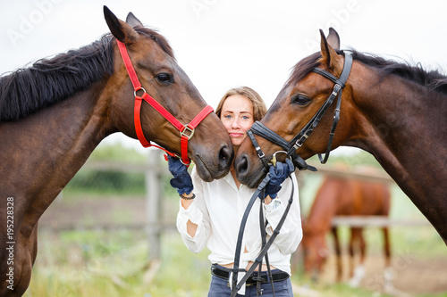 Young rider girl having fun with two her horses. Equestrian sport concept background