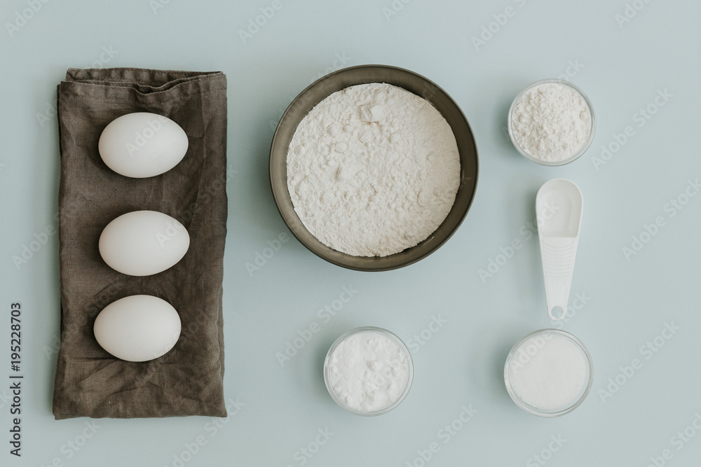 Fresh eggs, baking soda, sugar and flour over pastel background. Flat lay minimalistic baking background Fresh eggs, baking soda, sugar and flour over pastel background. Flat lay minimalistic baking background