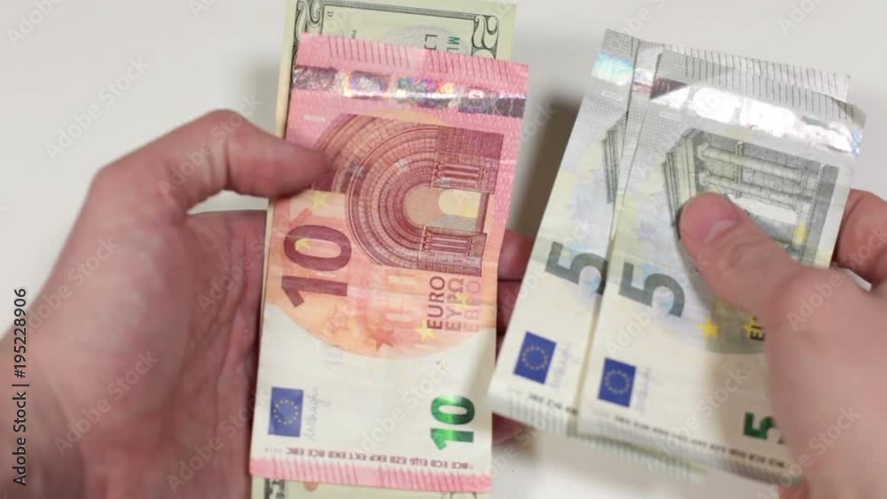 Caucasian hands counting euros and dollars cash, comparing twenty and fifty euros, white background Caucasian hands counting euros and dollars cash, comparing twenty and fifty euros, white background