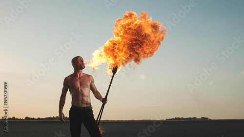 Male acrobat performing spitting fire act at the beach photo