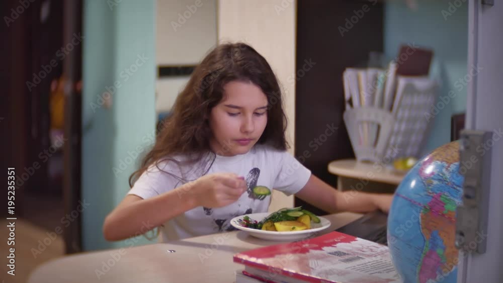Little girl sitting at the computer and eating chocolate. Little girl sitting at the computer and eating chocolate.