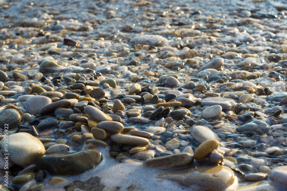 Obraz premium pebble stones on the sea beach, the rolling waves of the sea with foam