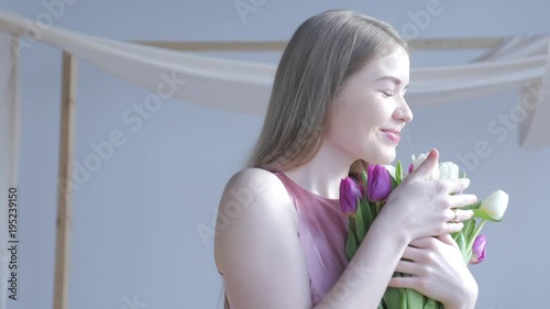Woman holding tulips and smiling to the camera. Beautiful Young Woman In Nice Spring Dress With A Bouquet Of Tulips. Woman showing a bunch of assorted flowers. Smiling girl with bunch of flowers. 