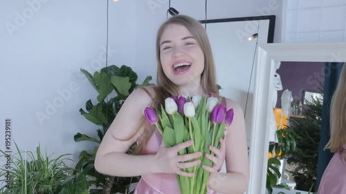 Woman holding tulips and smiling to the camera. Beautiful Young Woman In Nice Spring Dress With A Bouquet Of Tulips. Woman showing a bunch of assorted flowers. Smiling girl with bunch of flowers. 