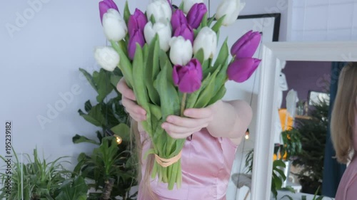 Woman holding tulips and smiling to the camera. Beautiful Young Woman In Nice Spring Dress With A Bouquet Of Tulips. Woman showing a bunch of assorted flowers. Smiling girl with bunch of flowers. 