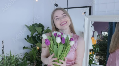 Woman holding tulips and smiling to the camera. Beautiful Young Woman In Nice Spring Dress With A Bouquet Of Tulips. Woman showing a bunch of assorted flowers. Smiling girl with bunch of flowers. 