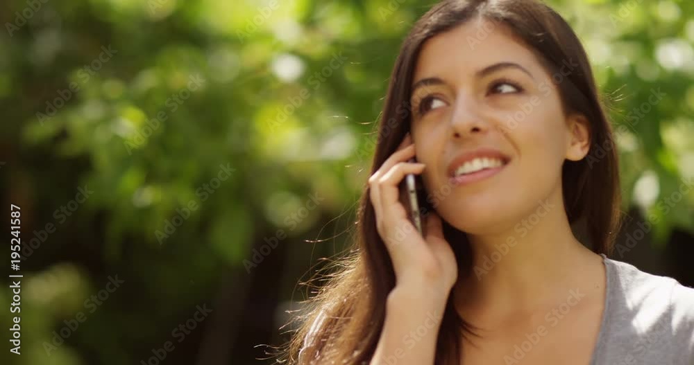 4K Beautiful smiling woman talking on cell phone outdoors in natural environment. Slow motion. 4K Beautiful smiling woman talking on cell phone outdoors in natural environment. Slow motion.