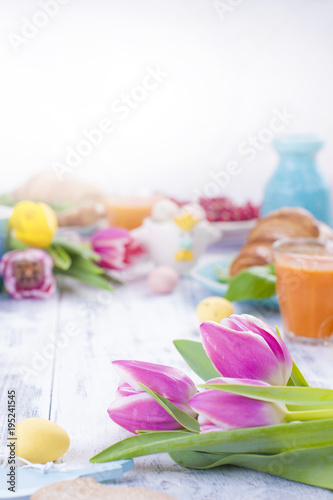 Easter breakfast of croissants and coffee, natural juice. Fresh spring tuips of pink color. White wooden table. Free space for text