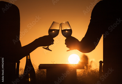 Couple celebrating outdoors with a glass of wine and beautiful sunset. Happy life moments, romance, concept. 