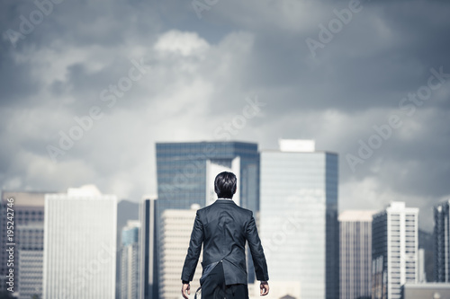 Man standing in the big city with storm clouds over head. Conquering adversity, challenging yourself concept. 