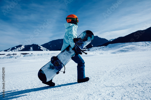 one snowboarder with snowboard walking on winter mountain ski slope