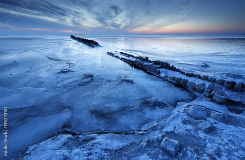 old wooden breakwater on frozen coast