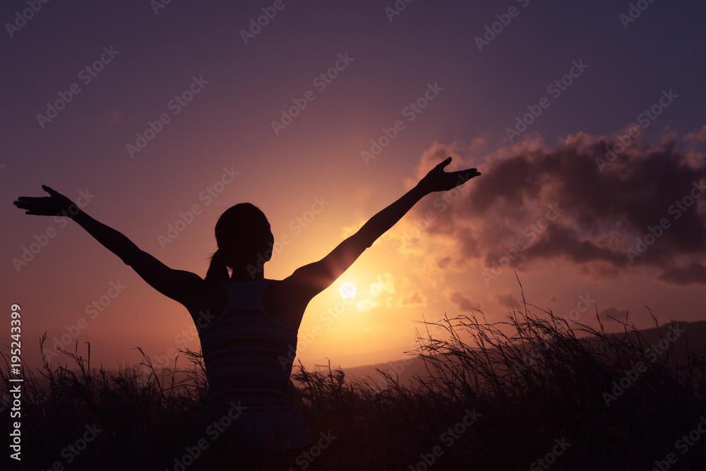 It's a new day! Young woman in a open field watching the sunrise. Joy, freedom, adventure concept. 