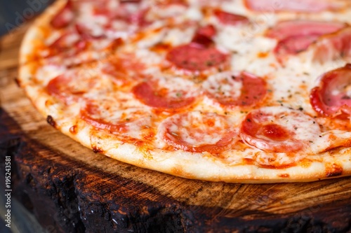 Appetizing fresh pizza with bacon, salami, ham and pepperoni, close up. Italian food, pizzeria concept