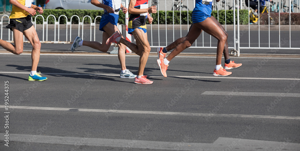 Fototapeta premium Legs of marathon runners running on city road