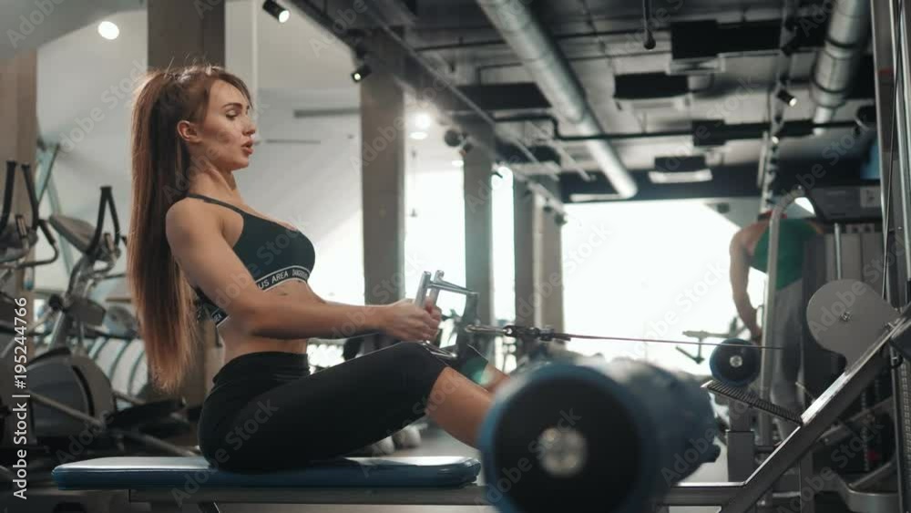 young sport woman girl athlete having hard workout on rowing machines in gym. Brunette sexy beautiful fit healthy female indoor training young sport woman girl athlete having hard workout on rowing machines in gym. Brunette sexy beautiful fit healthy female indoor training