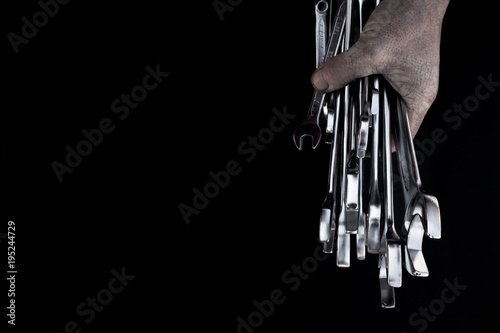 Man's hand holds steel wrenches on black background. Concept car service. Free space for text. photo